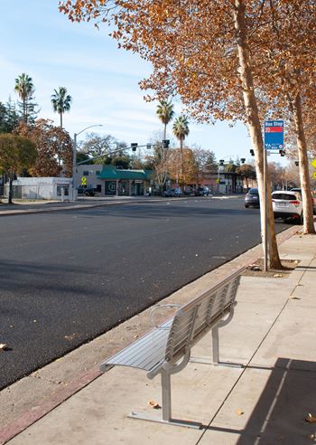 A street with a bench on the sidewalk.